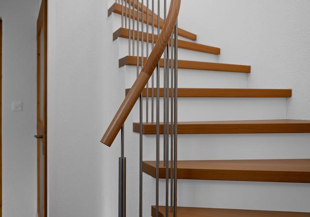 Das Bild zeigt einen Ausschnitt von einer schönen Holmentreppe in weiss mit Holztritten