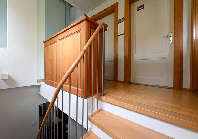 Das Bild zeigt den Handlauf einer schönen Holmentreppe in weiss mit Holztritten.